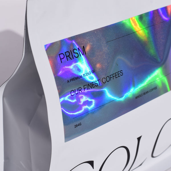 close up of new prism coffee in our new 10oz white whole bean coffee bags with reflective shimmery label