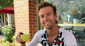 male athlete sitting outside of Color Coffee drinking his coffee in a yellow mug