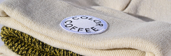 Color Coffee apparel represented here by a stack of creame and yellow heathered beanies with the new Color Coffee white circle logo patch