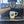 Load image into Gallery viewer, A white ceramic coffee mug with a black armadillo illustration sits on the drip tray of a black espresso machine with a wooden-handled portafilter in the foreground.

