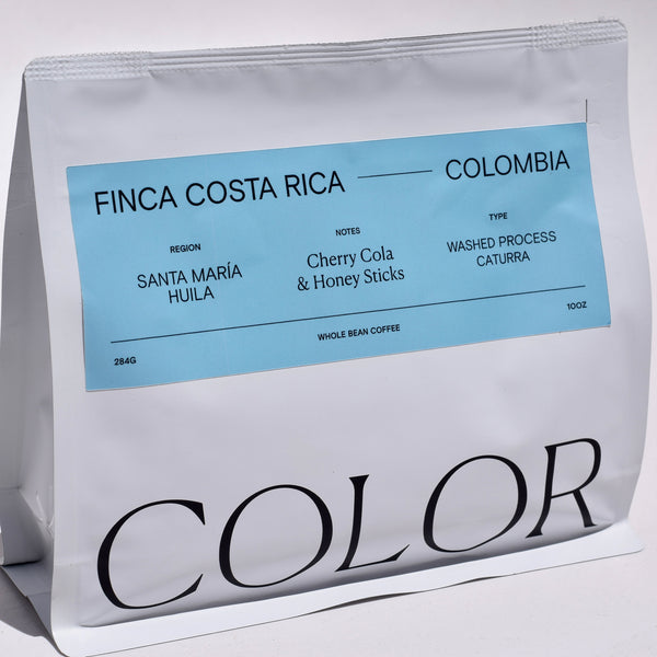 our 10oz white whole bean coffee bag with blue rectangle label and COLOR logo at the bottom