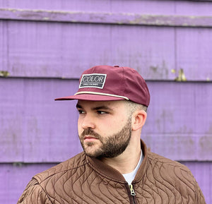 Man with a brown coat wearing an Eggplant 5 panel nylon hat