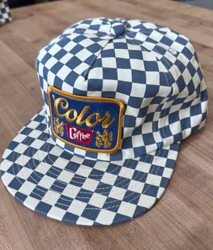Blue and white checkered cap with a colorful patch on a wooden surface