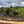 Load image into Gallery viewer, Hillside with greenery and a coffee drying bed under a cloudy sky
