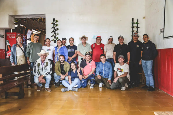 Group of people posing for a photo in a room with wooden floor and white walls.
