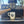 Load image into Gallery viewer, A white ceramic coffee mug with 'Color Coffee' printed in black script sits on the drip tray of a black and wood espresso machine.
