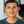 Load image into Gallery viewer, A close-up portrait of a man with dark hair wearing a dark green crewneck t-shirt, set against a softly blurred indoor background.
