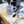 Load image into Gallery viewer, A white ceramic mug with a pink llama pattern sits on a light-colored countertop next to a paintbrush and a paint brush handle, with a coffee machine in the background.
