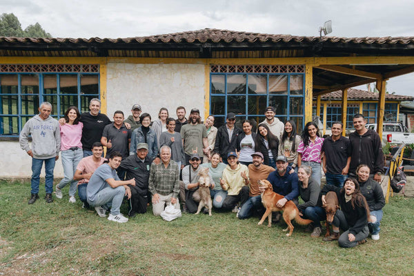Group of people and dogs posing in front of a building with a yellow facade.
