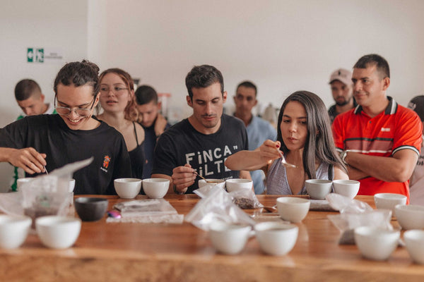 Group of people participating in a coffee tasting session at a wooden table.