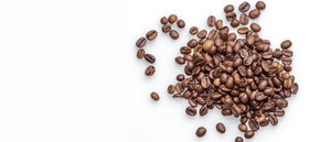 a messy pile of whole bean coffee beans on a white background