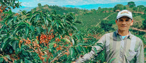 coffee farmer Carlos with coffee bean plant beside him and behind him
