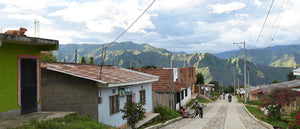 Colombian village with cobble stone road, some houses on the left and mountain ranges in the background