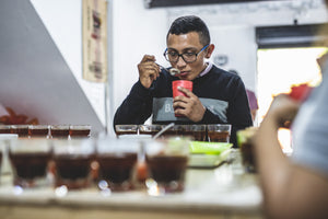 coffee farmer taste testing multiple coffee all in a row in glasses