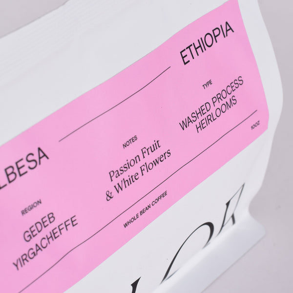 close up of Ethiopia whole bean coffee in our new white10oz bag with pink label
